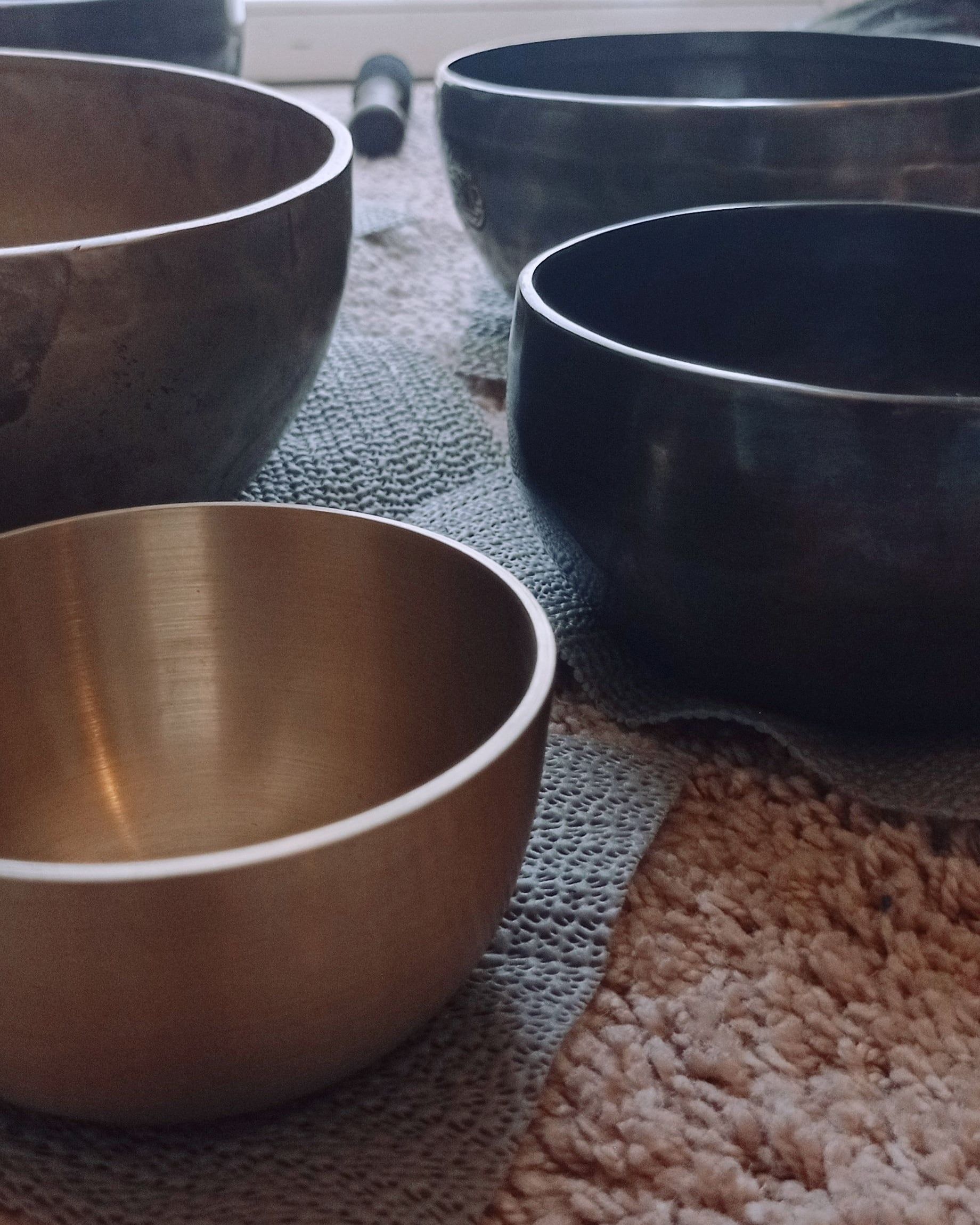 Bols tibétains posés sur des carrés de feutre, à la lumière douce d'une fenêtre